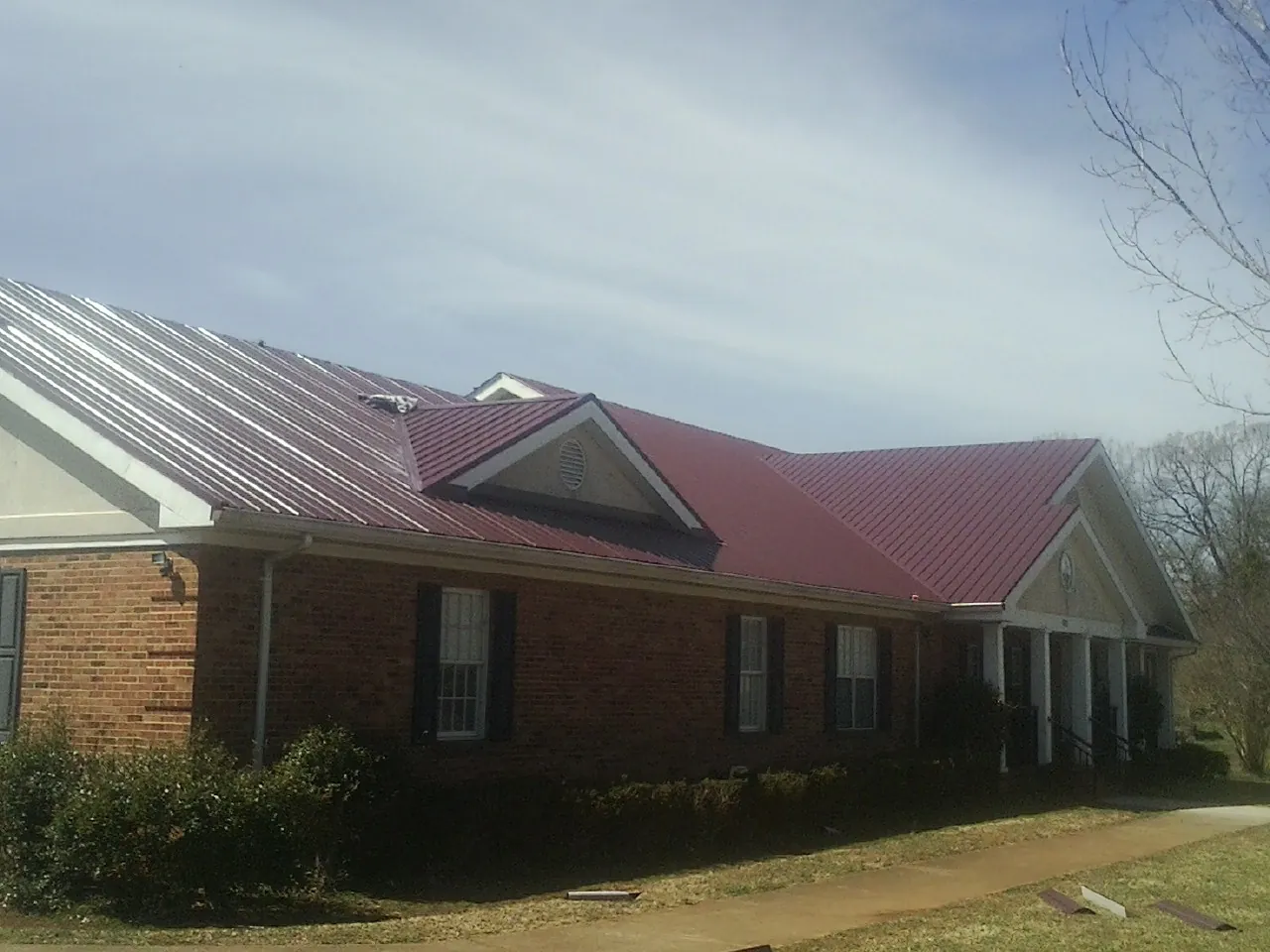 Red metal roof with gabled entries on a long brick building in Smithville Flats