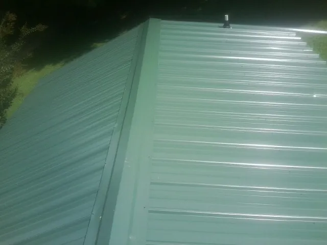 New green metal panels meeting at the ridge of a roof — Flat Roof Repair work by our crew in Smithville Flats