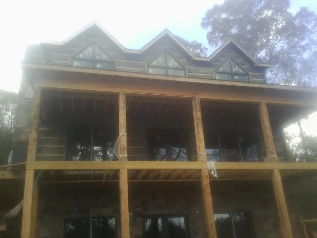 Dormers and porch framing on a large log home under construction — Roof Coating work by our crew in Smithville Flats