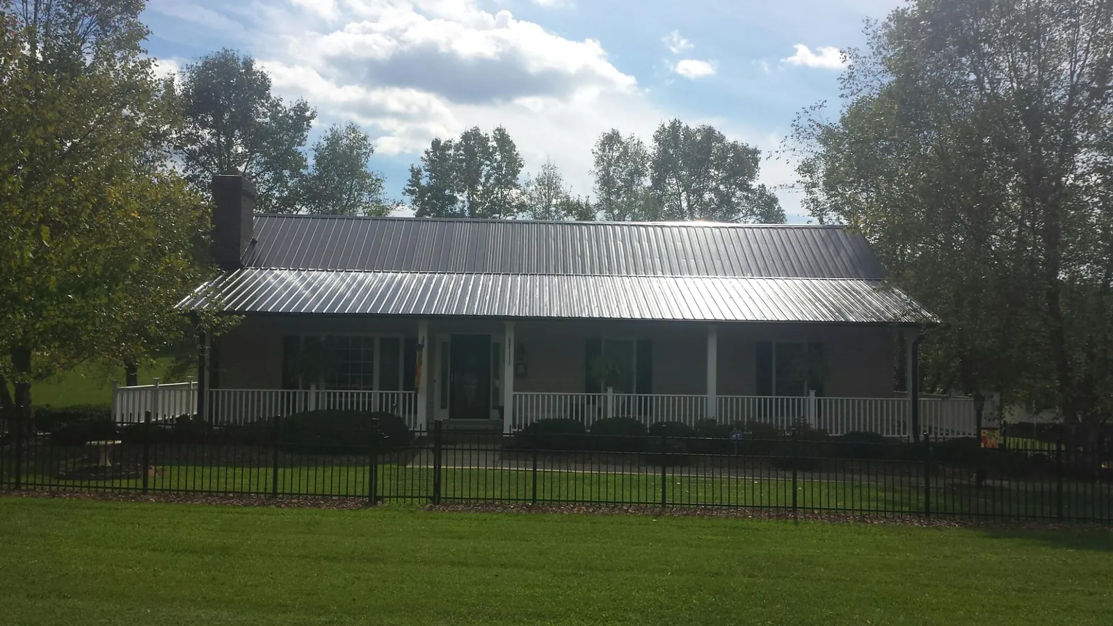 Gray metal roof on a brick ranch with a full width front porch — Gutter Guard Installation work by our crew in Smithville Flats