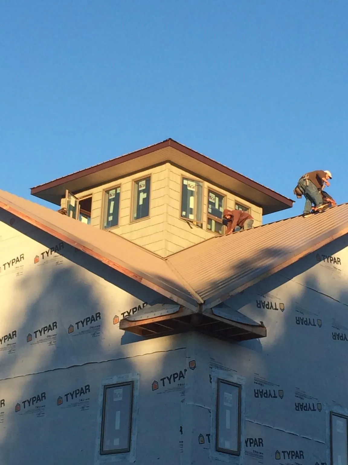 Roofers working around a rooftop cupola on a new metal roof at sunset — Roof Waterproofing in Smithville Flats by Roofing Brothers